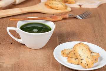 Hot and fresh green tea on wood with home made a small sweet cookie with black sesame.