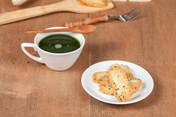 Hot and fresh green tea on wood with home made a small sweet cookie with black sesame.