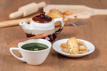 Hot and fresh green tea on wood with home made a small sweet cookie with black sesame.