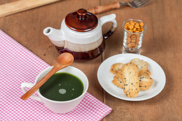 Hot and fresh green tea on wood with home made a small sweet cookie with black sesame.