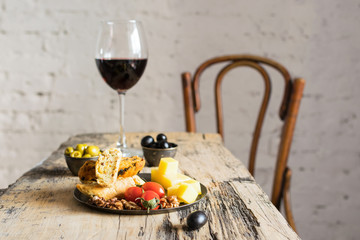 Glass of red wine and snacks on wooden table