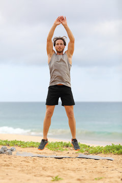Jump Squats fitness training. Athlete Man doing Jump Squat exercise workout. Male fitness instructor training on beach.