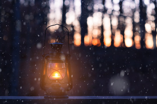 Vintage style lamp with a candle at snowy winter night