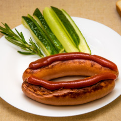 Fried sausage and cucumbers on a white plate.