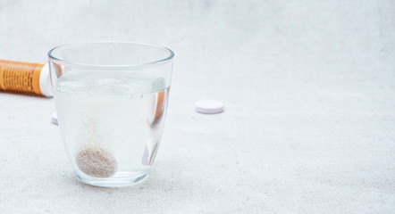 Effervescent tablet (vitamin) in a glass of water.