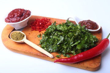 Fresh green cilantro, coriander leaves, tomato paste, chili pepper and spices on a wooden board. Ingredients for meat sauce.