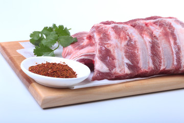 Raw pork ribs with herbs and spices on wooden board. Ready for cooking.