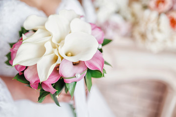 Close-up of a bride holding a wedding bouquet with flowers calla