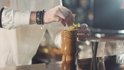 20s bartender is preparing cocktail in a night bar