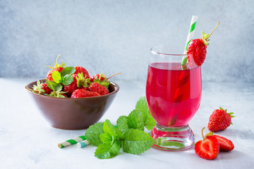 Refreshing summer drink strawberry juice, fresh strawberries and mint on a gray stone or slate background. Healthy breakfast on the kitchen table.