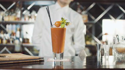 Bartender in hat is preparing cocktail in bar