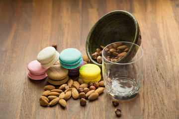 Tasty macaroons and cup of milk with almond on wooden background. Selective focus