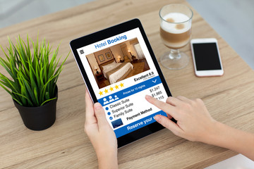 woman hand holding computer tablet with app hotel booking screen