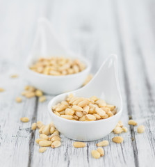Portion of Pine Nuts on wooden background (selective focus)