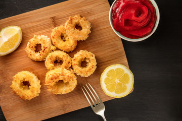 Calamari rings, red sauce, fork, lemon, copyspace