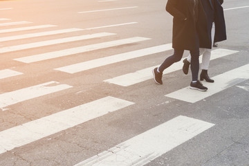 close-up on unidentified people legs crossing street with soft light flare