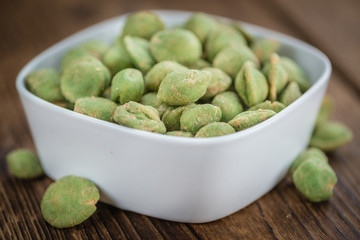 Portion of Wasabi coated Peanuts on wooden background (selective focus)