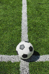 close up view of soccer ball lying on green soccer pitch
