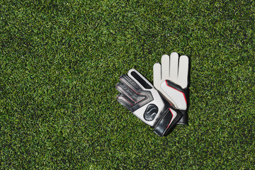 top view of goalkeeper gloves lying on soccer pitch