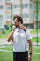 portrait of soccer referee whistling in whistle on soccer pitch during game
