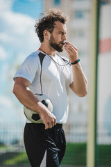 side view of soccer referee whistling in whistle on soccer pitch during game