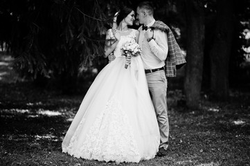 Attractive young wedding couple walking and posing in the park on a sunny day. Black and white photo.