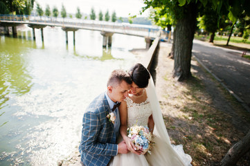 Naklejka premium Awseome-looking wedding couple sitting next to the lake on a sunny day.