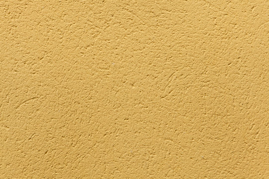 Yellow ochre painted stucco wall. Background texture.