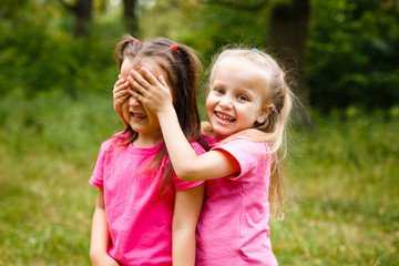 Younger sister standing behind sister, covering her eyes