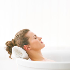 Obraz na płótnie Canvas Relaxed young woman laying in bathtub