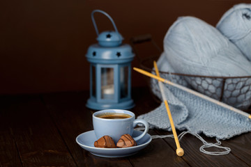 Knitting from light blue yarn. Cup of coffee and chocolates.