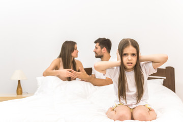 The unhappy girl sit on the background of the arguing parents