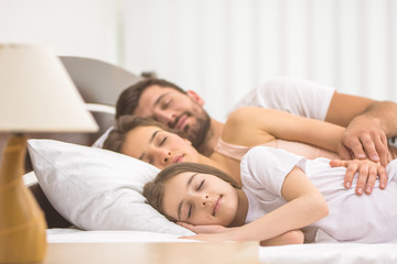 Obraz na płótnie Canvas The happy family sleeping on the bed