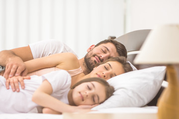 Obraz na płótnie Canvas The happy family sleeping on the comfortable bed