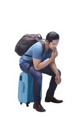 Portrait of asian tourist sitting on suitcase thinking