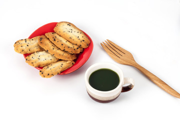 Hot green tea and home made a small sweet cookie with .black sesame, typically round, flat, and crisp.Cookie on .white.