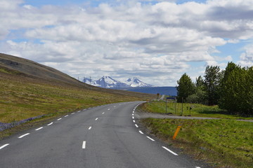Scenic Icelandic road for cars with green mountains in the background 