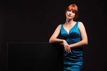 Young confident woman portrait of a confident businesswoman showing presentation, pointing placard black background. Ideal for banners, registration forms, presentation, landings, presenting concept.