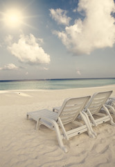 Fototapeta na wymiar Empty beach chairs on sand by the sea , retro effect