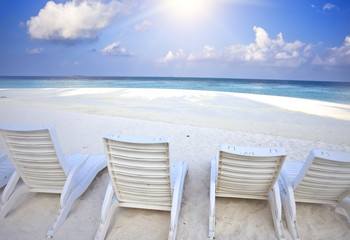 Empty beach chairs on sand by the sea