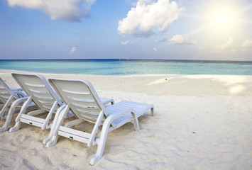 Fototapeta na wymiar Empty beach chairs on sand by the sea