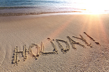 On a beach it is written holiday