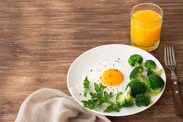 Fried eggs with broccoli and greens. Delicious homemade breakfast. On a wooden table, selective focus