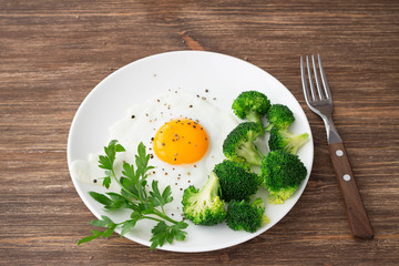 Fried eggs with broccoli and greens. Delicious homemade breakfast. On a wooden table, selective focus