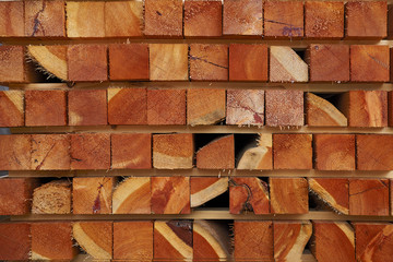 Pattern of stacked square wooden beams at sawmill lumberyard.