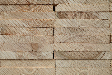 Close-up pattern of stacked rectangular wooden beam timber at sawmill lumberyard.
