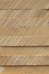 Close-up pattern of stacked rectangular wooden beam timber at sawmill lumberyard.