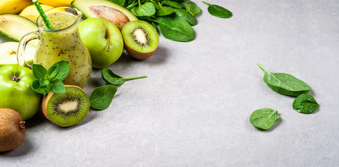 Healthy green smoothie in bottle and ingredients. Healthy food, superfoods, detox, diet. Kiwi, apple, spinach, avocado, banana and mint. Vegetarian food background