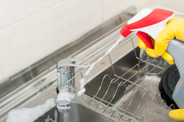Housemaid with disinfecting spray in the kitchen