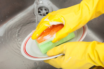 Cleaning lady or housewife with sponge washing dish